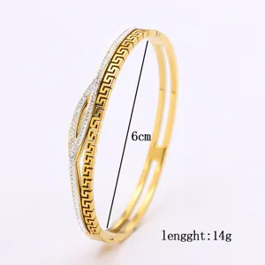 Macro di un bracciale in acciaio al titanio dorato con motivo greco e strass