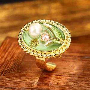 Detail view of vintage enamel ring with natural pearl and lily of the valley motif