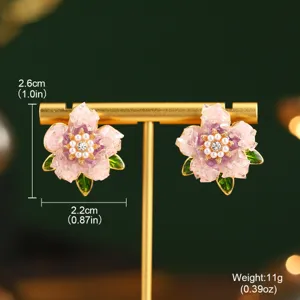 Gros plan détaillé de boucles d'oreilles fleurs en émail rose avec perles et cristaux
