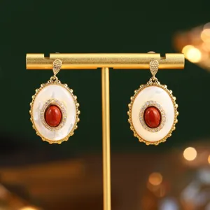 Gros plan de boucles d'oreilles ovales vintage avec nacre blanche et pierre rouge