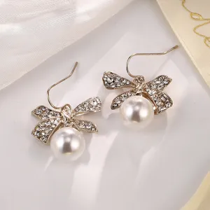 Detailansicht eleganter goldfarbener Schleifenohrringe mit Kristallen und Perle