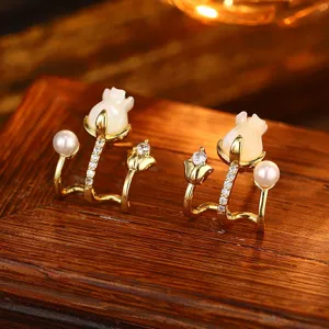 Detailaufnahme von Goldblumen-Ohrsteckern mit Perlen und Zirkonien