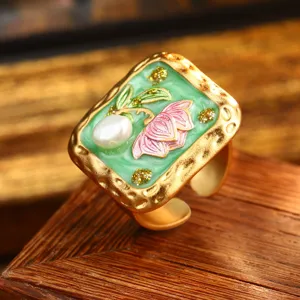 Detail view of a vintage floral enamel ring with a baroque pearl and gold hammered finish