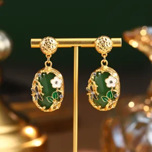 Détail de boucles d'oreilles vintage en émail avec pierre verte et libellule