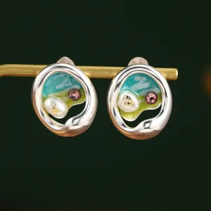 Gros plan de boucles d'oreilles en émail avec perles naturelles et feuilles d'or