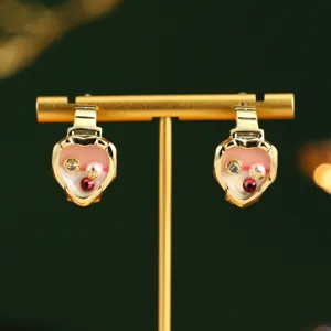 Gros plan de boucles d'oreilles cœur en émail avec détails perle et pierre précieuse