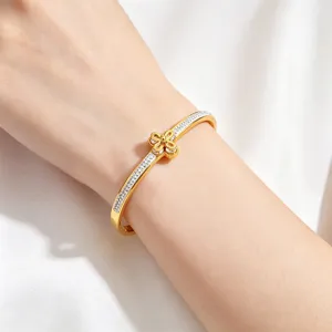Detailed view of gold stainless steel bangle featuring pavé crystals and flower charm