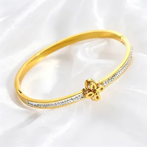 Close-up detail of luxury gold stainless steel bangle with rhinestones and flower charm