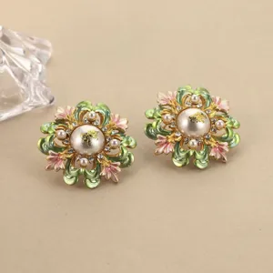 Nahaufnahme von Vintage-Ohrringen mit Blumen aus Emaille, Perlen und Goldakzenten.