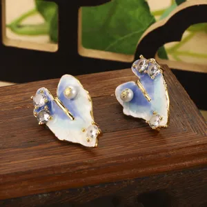 Détail des boucles d'oreilles papillon en émail bleu avec perles et cristaux fins