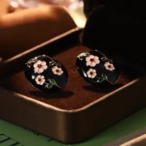 Elegant vintage-style oval enamel earrings with pink floral patterns on black
