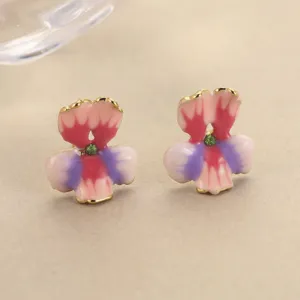 Close-up view of enamel flower earrings with gradient pink petals and green gemstone