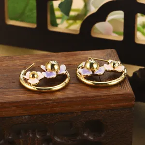 Détail montrant d'élégantes boucles d'oreilles créoles fleurs en émail doré