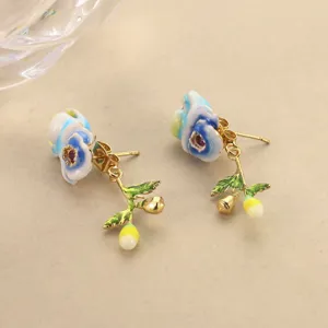 Detailed view of handcrafted blue enamel flower earrings with golden leaf accents
