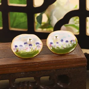 Gros plan de boucles d'oreilles fleur en émail vintage avec perles sur support