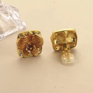 Detailansicht der Vintage-Clip-Ohrringe mit Emaille-Orchideenblüten in Gold-Finish.