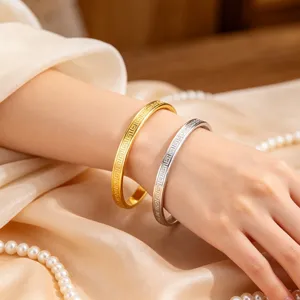 Primo piano di bracciali in acciaio inossidabile oro e argento con motivo greco.