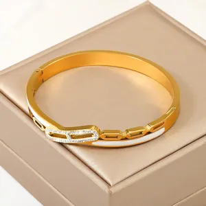 Primer plano de brazalete de acero de titanio dorado con diamantes y detalles blancos