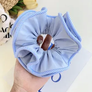 Close-up of large blue fabric scrunchie with blue and white striped edges