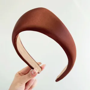 Detalle de cerca de una diadema de satén acolchada marrón con un diseño vintage.