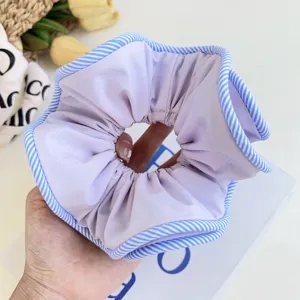 Close-up of lavender fabric scrunchie with blue and white striped piping detail
