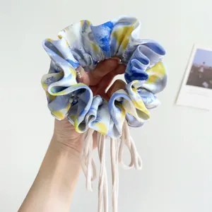 Detail view of an elegant blue and yellow oil painting style tie-dye silk scrunchie