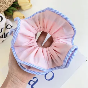 Macro detail of a pink fabric scrunchie with blue striped edges for hair styling