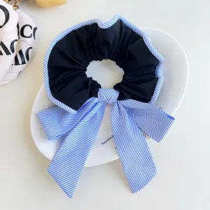Vista de cerca del coletero de tela a rayas azules con lazo elegante para peinados de mujer.