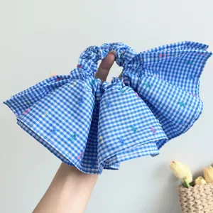 Detalle de coletero de cuadros azules con bordados coloridos y diseño de volantes grandes