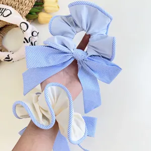 Detalle de primer plano de coleteros con lazo a rayas azul claro usados en la muñeca de una mujer