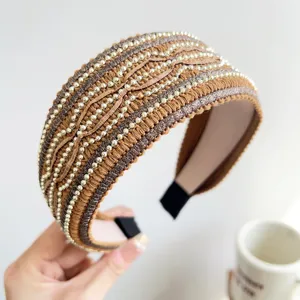 Primo piano di un cerchietto intrecciato marrone con file di perline dorate e glitter