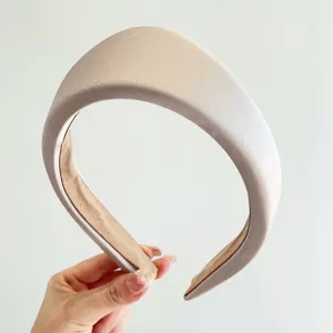 Primer plano de una elegante diadema triangular acolchada en satén champán para mujer
