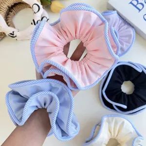 Detailed macro view of oversized fabric hair scrunchies featuring blue striped piping edges