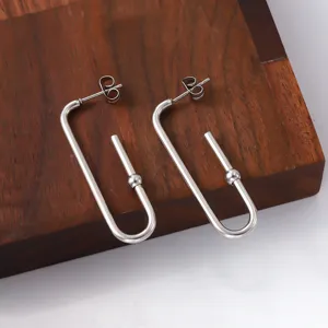 Vue macro détaillée de boucles d'oreilles minimalistes en acier inoxydable avec perle ronde