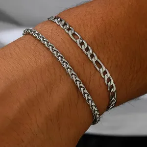 Nahaufnahme von Edelstahl Figaro- und Weizenketten-Armbändern an einem Männerhandgelenk