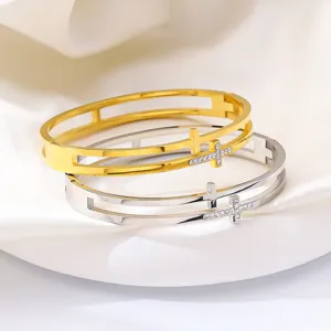 Gros plan de bracelets croix évidés or et argent avec strass sur de la soie fine