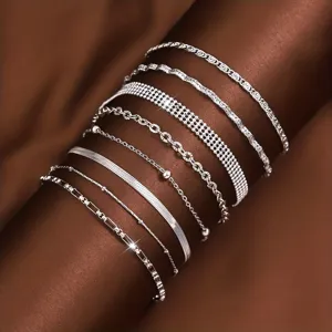 Set aus polierten silbernen Edelstahl-Armbändern an einem dunklen Modellarm gezeigt