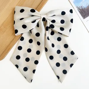 Gros plan d'un grand nœud à cheveux crème avec des pois noirs élégants.