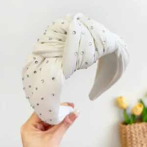 Detailopname van een witte geknoopte stoffen hoofdband met glitter steentjes