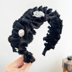 Detail van een elegante zwarte geribbelde hoofdband met parels en zilveren bloemen