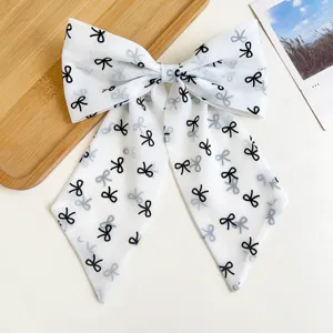 Gros plan d'un grand nœud à cheveux en mousseline blanche avec motifs noirs