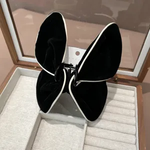 Vue détaillée d'une pince à cheveux papillon en velours noir avec bordure blanche