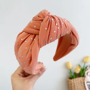Detailopname van een koraalrode geknoopte stoffen hoofdband met fonkelende strass