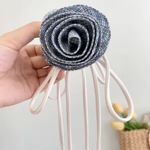 Primo piano di una molletta per capelli a forma di rosa scozzese blu con lunghi nastri