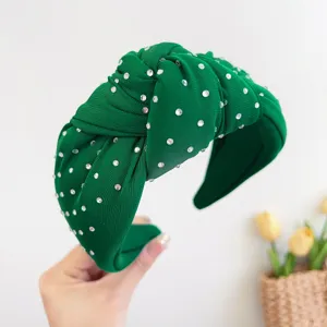 Detailopname van een smaragdgroene geknoopte stoffen hoofdband met fonkelende strassteentjes