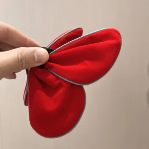 Gros plan d'une pince à cheveux papillon en velours rouge avec bordure grise contrastée