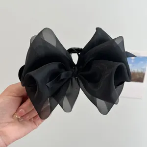 Detalle de pinza de pelo con lazo de malla negra y textura de tela fina
