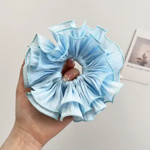 Detail eines hellblauen übergroßen gerafften Organza-Haargummis mit Stofflagenstruktur