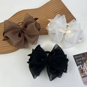 Tres pinzas grandes para el pelo con lazo de malla en marrón, blanco y negro en bandeja