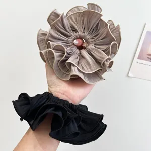 Detailansicht der eleganten plissierten Stofftextur der übergroßen gerafften Haargummis.